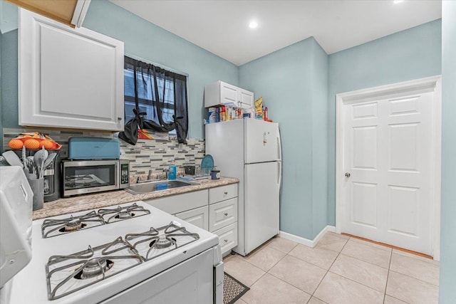 kitchen featuring white appliances, white cabinetry, tasteful backsplash, sink, and light tile patterned floors