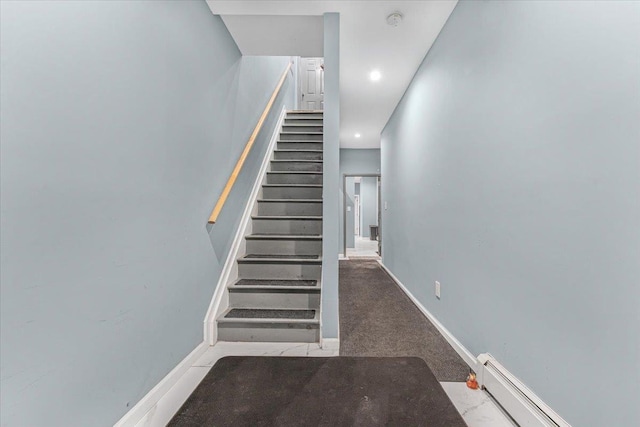 stairway with carpet floors and a baseboard heating unit