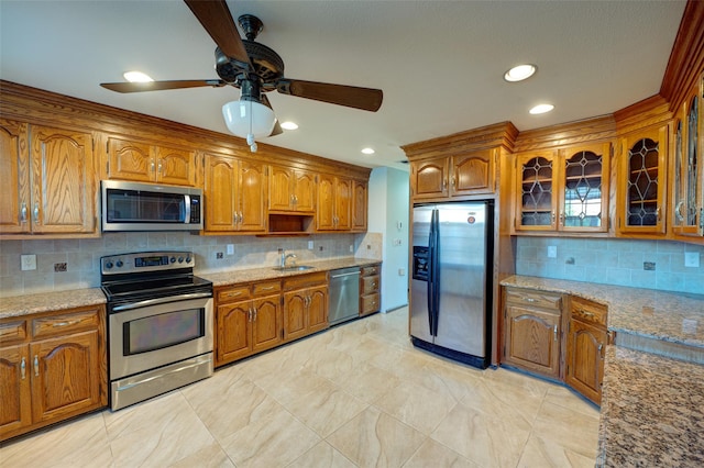 kitchen with sink, ceiling fan, appliances with stainless steel finishes, tasteful backsplash, and light stone counters