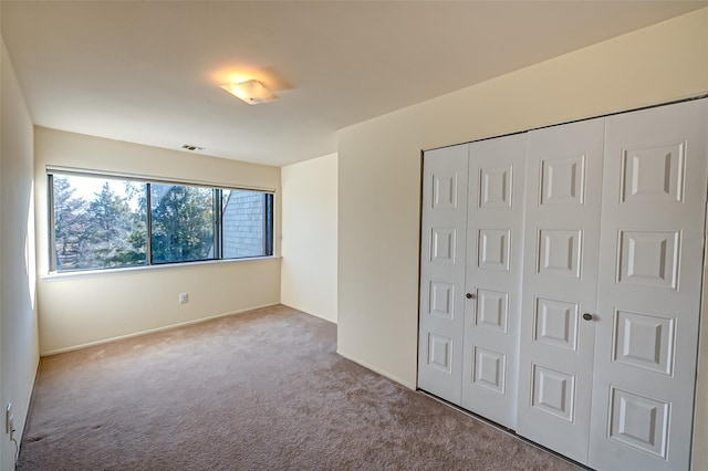 unfurnished bedroom featuring light colored carpet and a closet