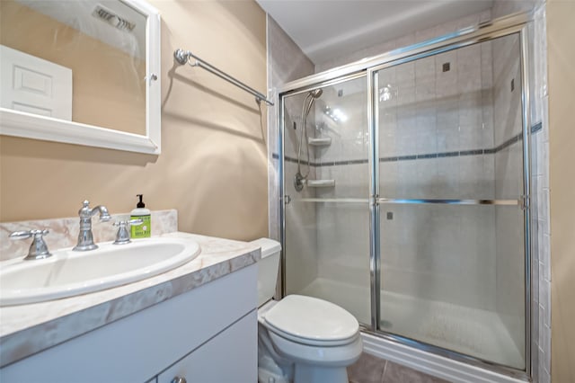 bathroom with tile patterned flooring, vanity, toilet, and a shower with door