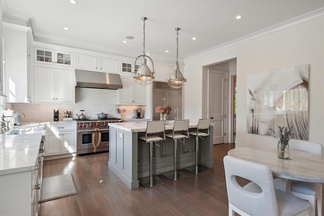 kitchen featuring light stone countertops, premium appliances, white cabinetry, and a kitchen island