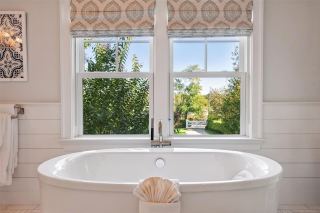 bathroom featuring tile patterned floors, wood walls, and a tub to relax in