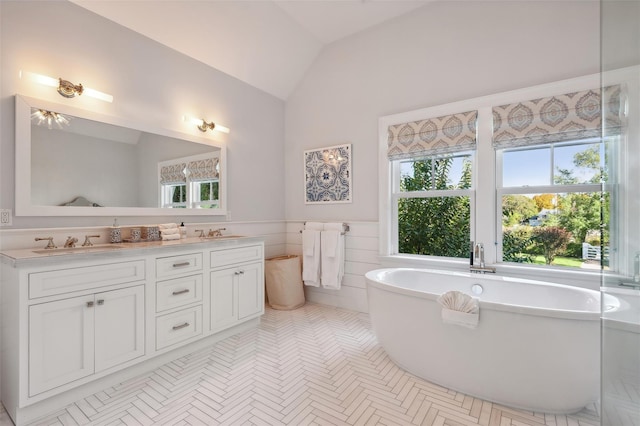 bathroom with a bathing tub, vanity, tile patterned floors, and vaulted ceiling