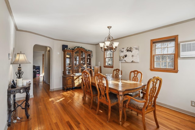 dining space with ornamental molding, an AC wall unit, hardwood / wood-style floors, and a chandelier