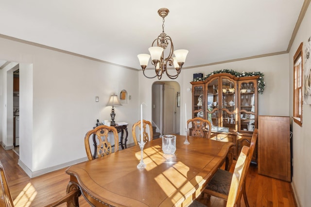 dining space with wood-type flooring, crown molding, and a chandelier