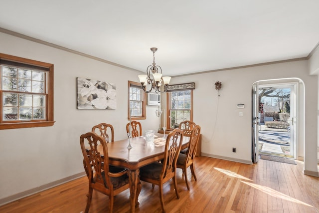 dining area with crown molding, a wall mounted air conditioner, a notable chandelier, and light hardwood / wood-style flooring