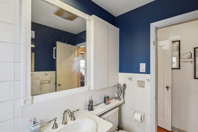 bathroom featuring tile walls, sink, and toilet