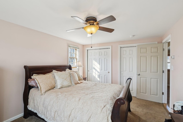 bedroom with ceiling fan, carpet flooring, and two closets