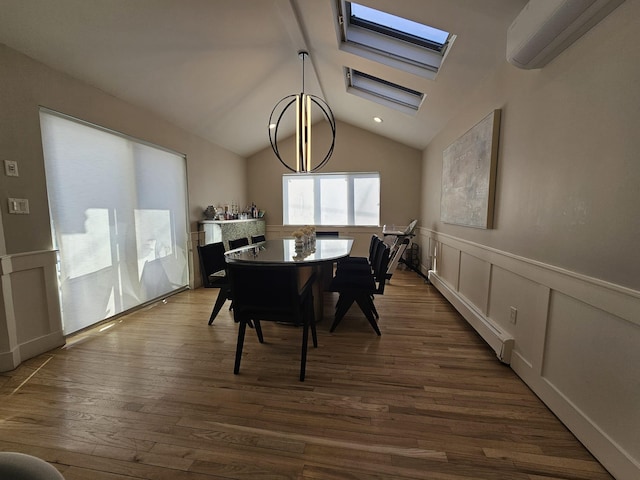 dining area featuring dark hardwood / wood-style floors, a wall mounted air conditioner, vaulted ceiling with skylight, a baseboard radiator, and a chandelier