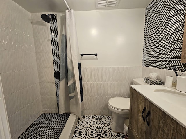 bathroom with tile walls, tile patterned flooring, vanity, curtained shower, and toilet