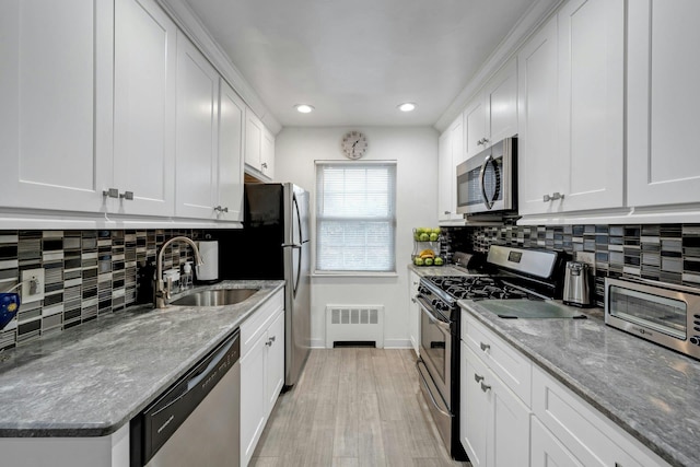 kitchen with sink, white cabinets, light stone counters, decorative backsplash, and appliances with stainless steel finishes