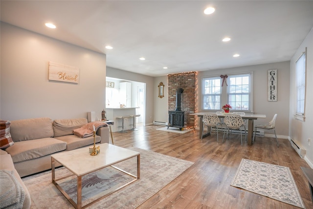 living room with a wood stove, light hardwood / wood-style flooring, and a baseboard radiator