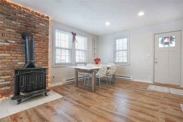 dining area with light wood-type flooring, baseboard heating, and a wood stove