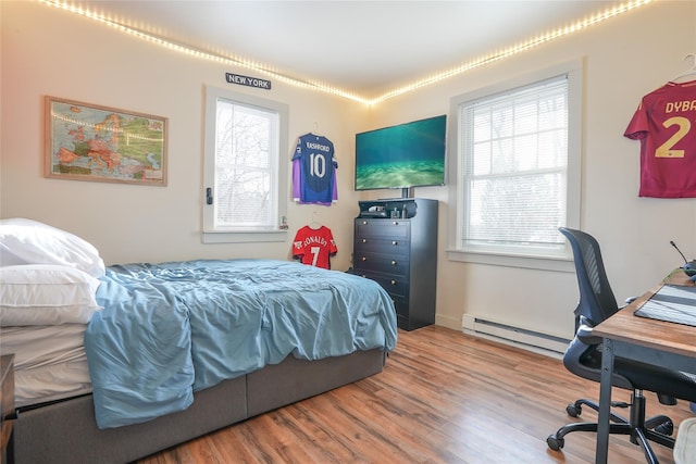 bedroom featuring baseboard heating and wood-type flooring