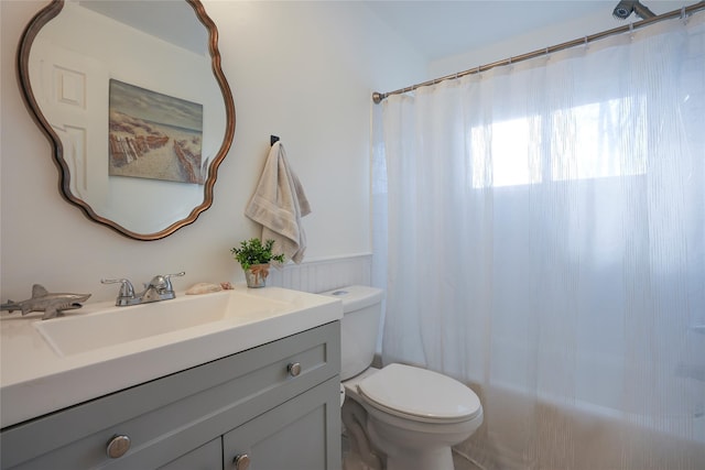 bathroom featuring toilet, vanity, and a shower with curtain