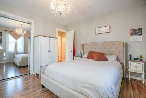 bedroom featuring an inviting chandelier and dark hardwood / wood-style flooring