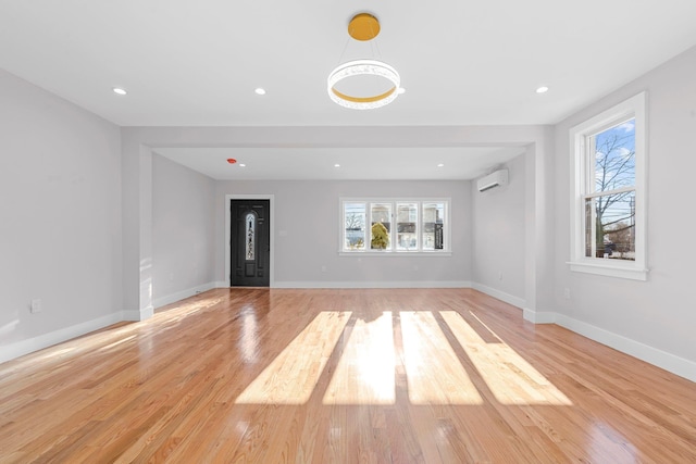 interior space with a wall mounted AC and light hardwood / wood-style floors