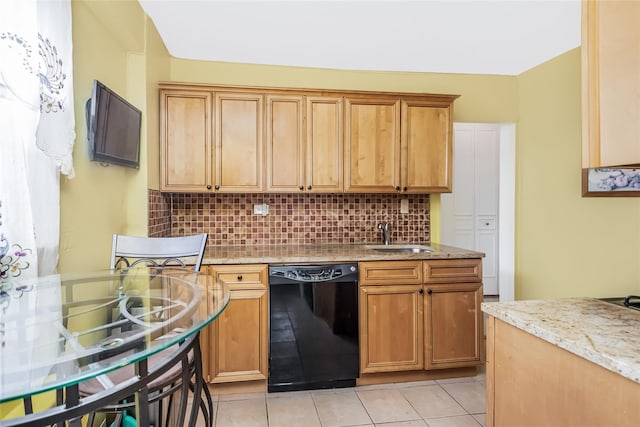 kitchen with sink, tasteful backsplash, light stone counters, light tile patterned floors, and black dishwasher