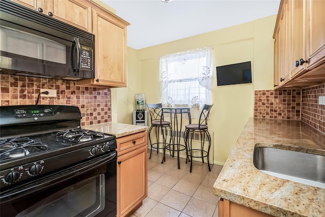 kitchen featuring sink, decorative backsplash, light tile patterned floors, light stone counters, and black appliances