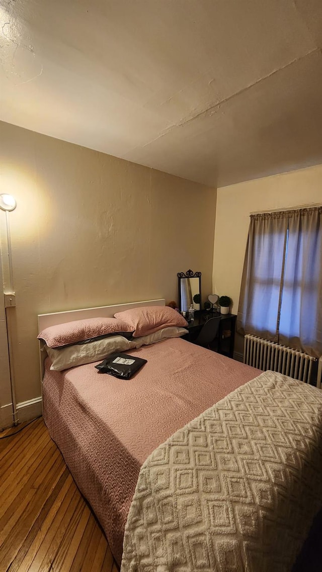 bedroom featuring radiator and wood finished floors