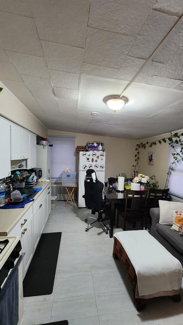 interior space featuring light countertops, gas range oven, freestanding refrigerator, and white cabinets