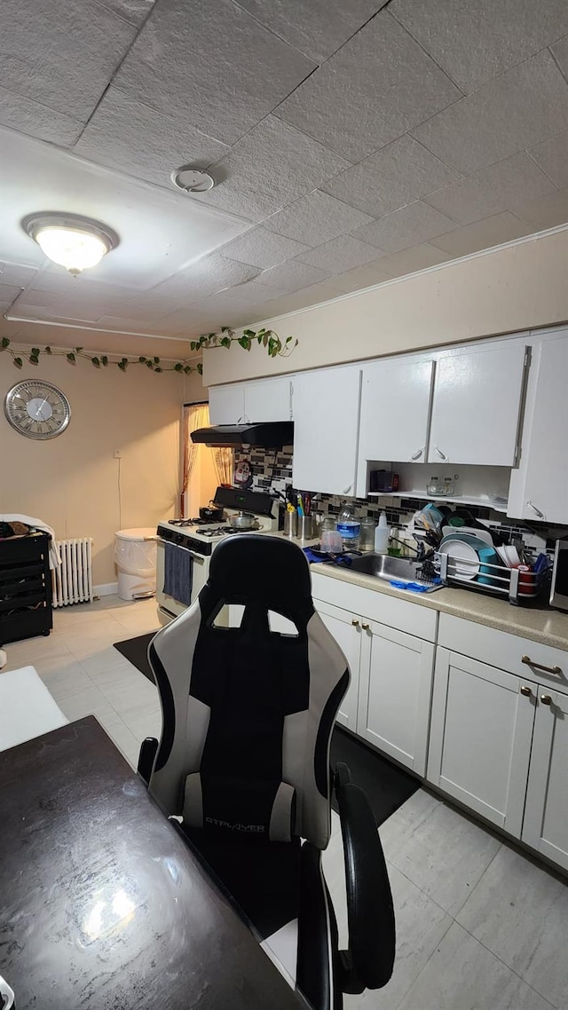 kitchen with light countertops, white cabinetry, a sink, and white gas range oven