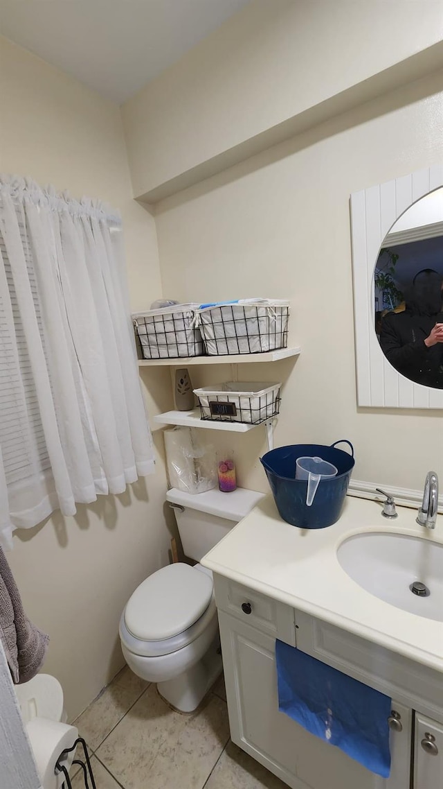 half bath with toilet, vanity, and tile patterned floors