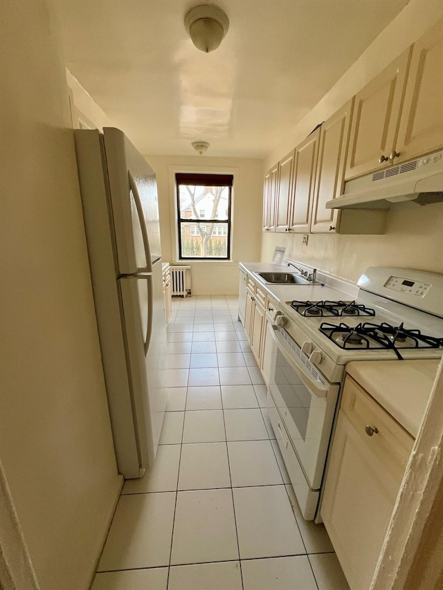 kitchen with sink, light tile patterned floors, radiator, and white appliances