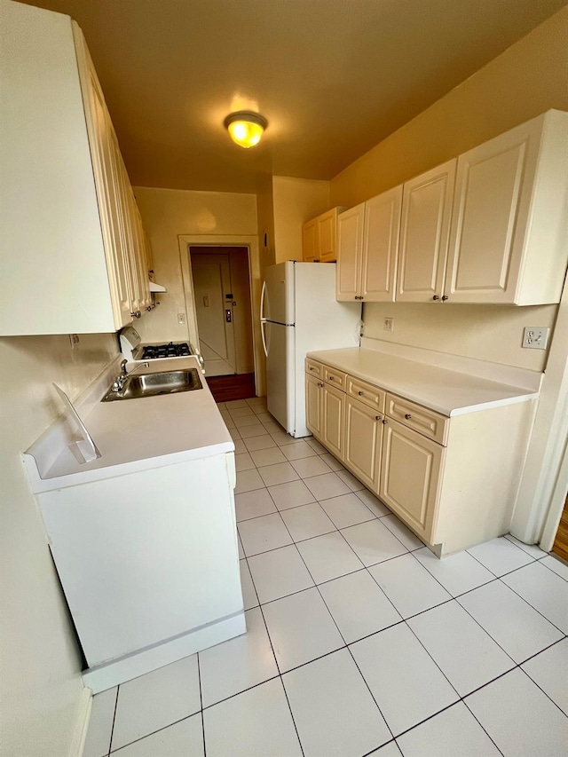 kitchen featuring washer / dryer, sink, white fridge, and light tile patterned floors