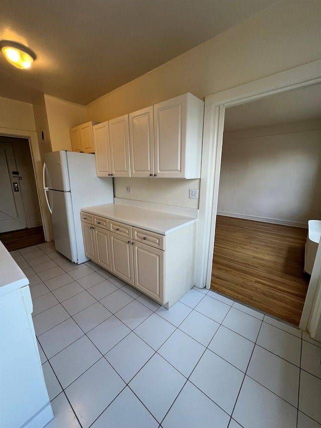 kitchen with white cabinetry, light tile patterned floors, and white fridge