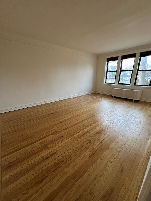 unfurnished room featuring plenty of natural light, radiator, and light hardwood / wood-style floors