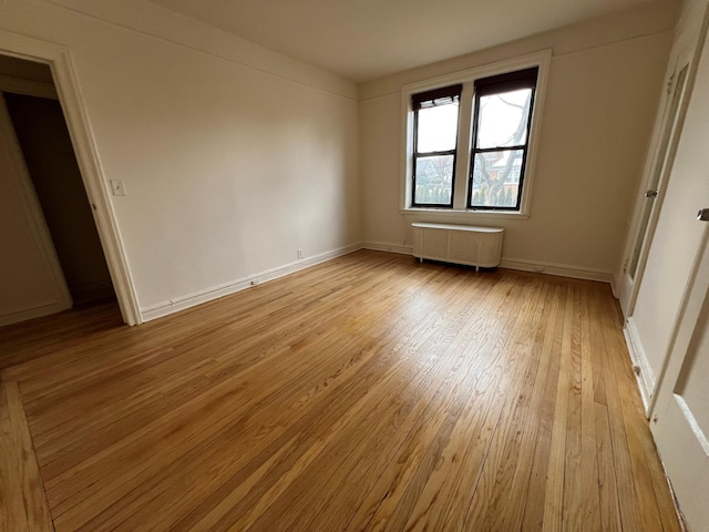 unfurnished bedroom with radiator heating unit and light hardwood / wood-style floors