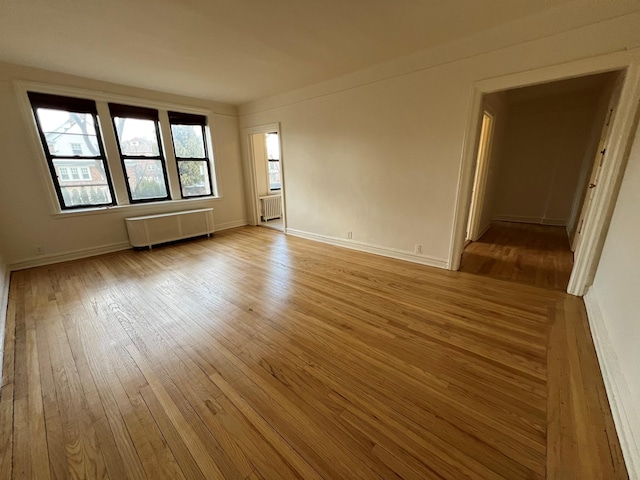 unfurnished room with radiator heating unit and light wood-type flooring