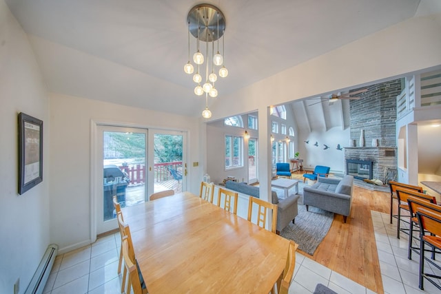 dining area with a fireplace, a baseboard radiator, lofted ceiling, and light tile patterned floors