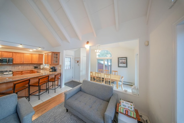 living room featuring sink, an inviting chandelier, vaulted ceiling with beams, light wood-type flooring, and a baseboard radiator