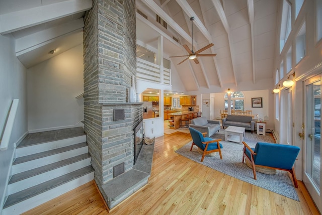 living room featuring a fireplace, ceiling fan, light hardwood / wood-style flooring, high vaulted ceiling, and beam ceiling