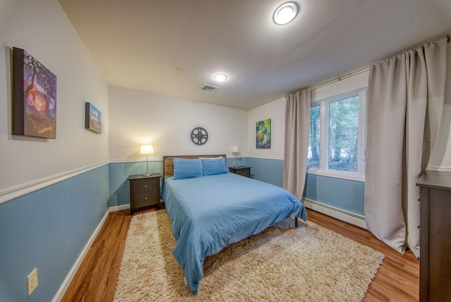 bedroom featuring baseboard heating and light hardwood / wood-style floors