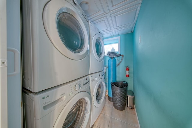 laundry room featuring light tile patterned flooring and stacked washer / dryer