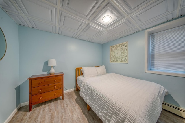 bedroom featuring light wood-type flooring and a baseboard radiator