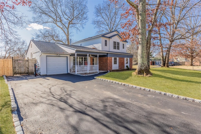 view of front of home with covered porch, a front yard, and a garage