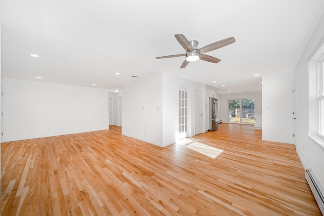 unfurnished living room featuring ceiling fan, light wood-type flooring, and a baseboard heating unit