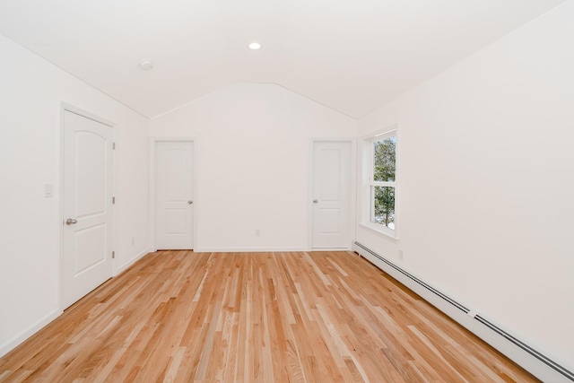 unfurnished room with lofted ceiling, a baseboard heating unit, and light hardwood / wood-style flooring