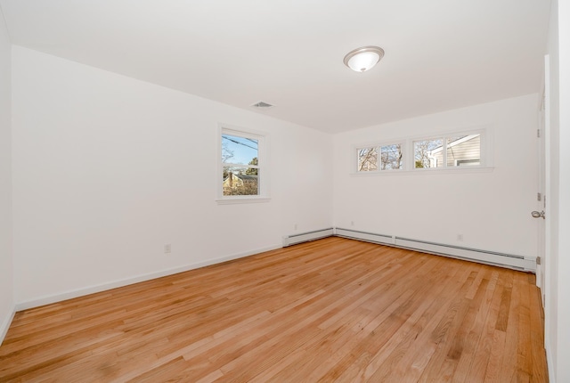 empty room with a healthy amount of sunlight, light wood-type flooring, and a baseboard radiator