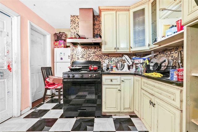 kitchen with wall chimney range hood, tasteful backsplash, black range with gas stovetop, white fridge, and cream cabinetry