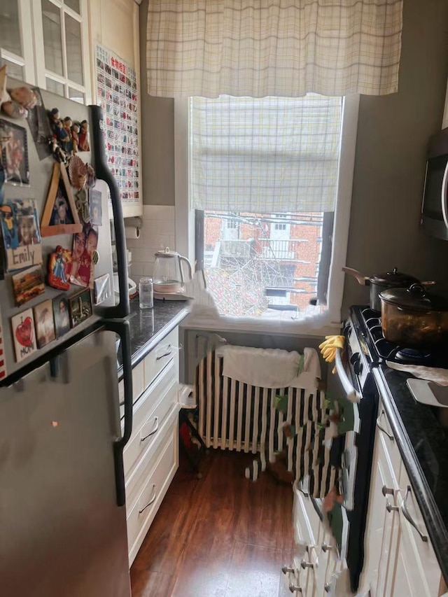 kitchen featuring white cabinets, decorative backsplash, dark hardwood / wood-style floors, and stainless steel appliances