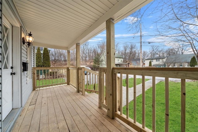 wooden terrace featuring a yard and covered porch