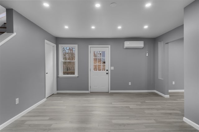 foyer entrance with light wood-type flooring and a wall unit AC