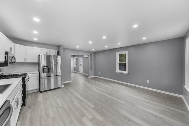 kitchen with white cabinetry, stainless steel appliances, light stone counters, light hardwood / wood-style flooring, and tasteful backsplash