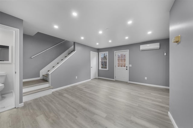 unfurnished living room with a wall mounted AC and light wood-type flooring